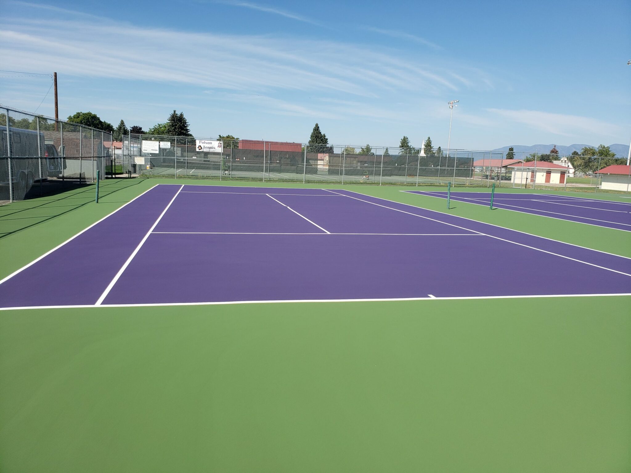 A new tennis court complex with fencing that includes green, purple, and white colors.