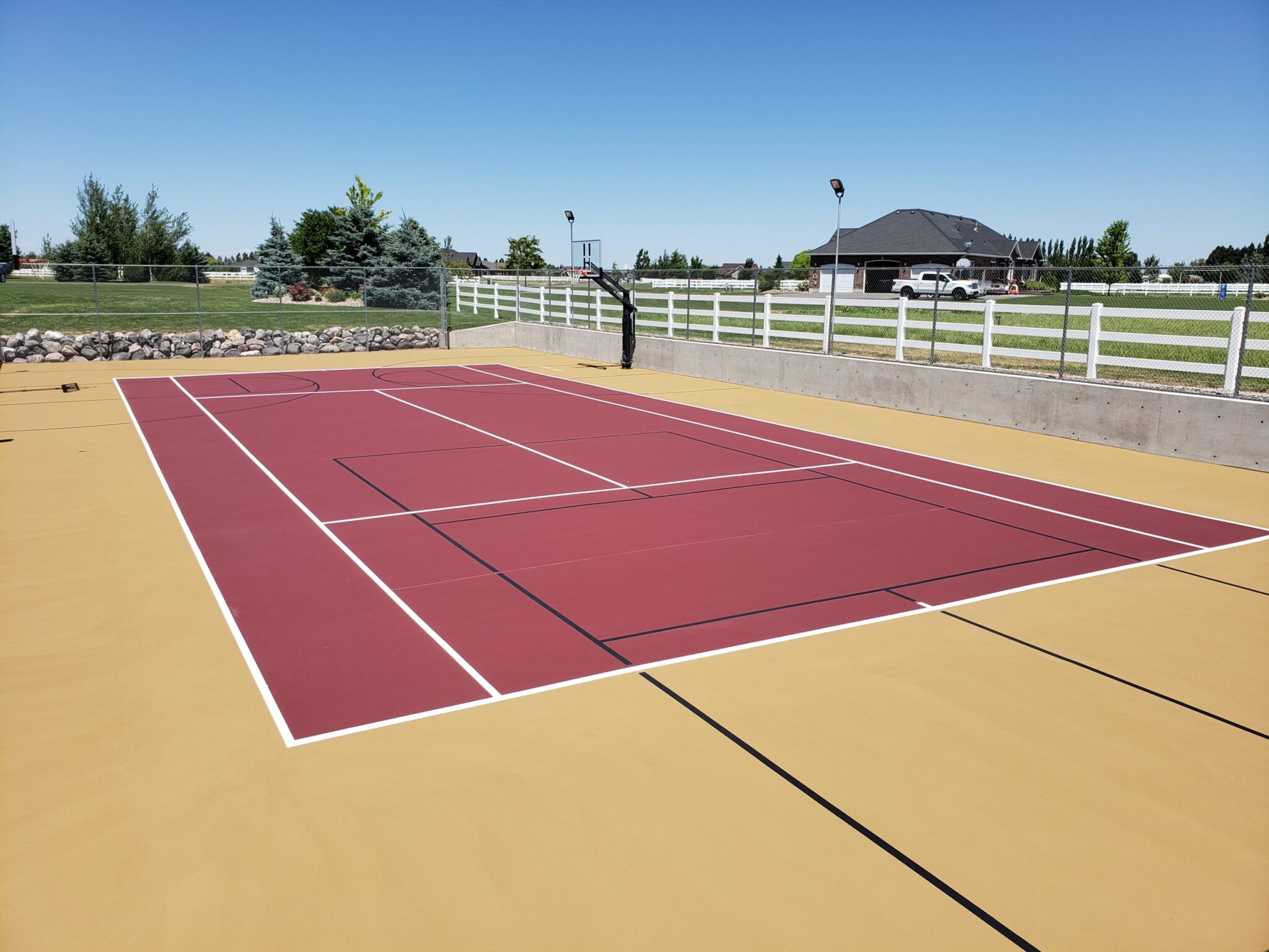A newly surfaced tennis, pickleball, and basketball court with red, white, and tan colors.