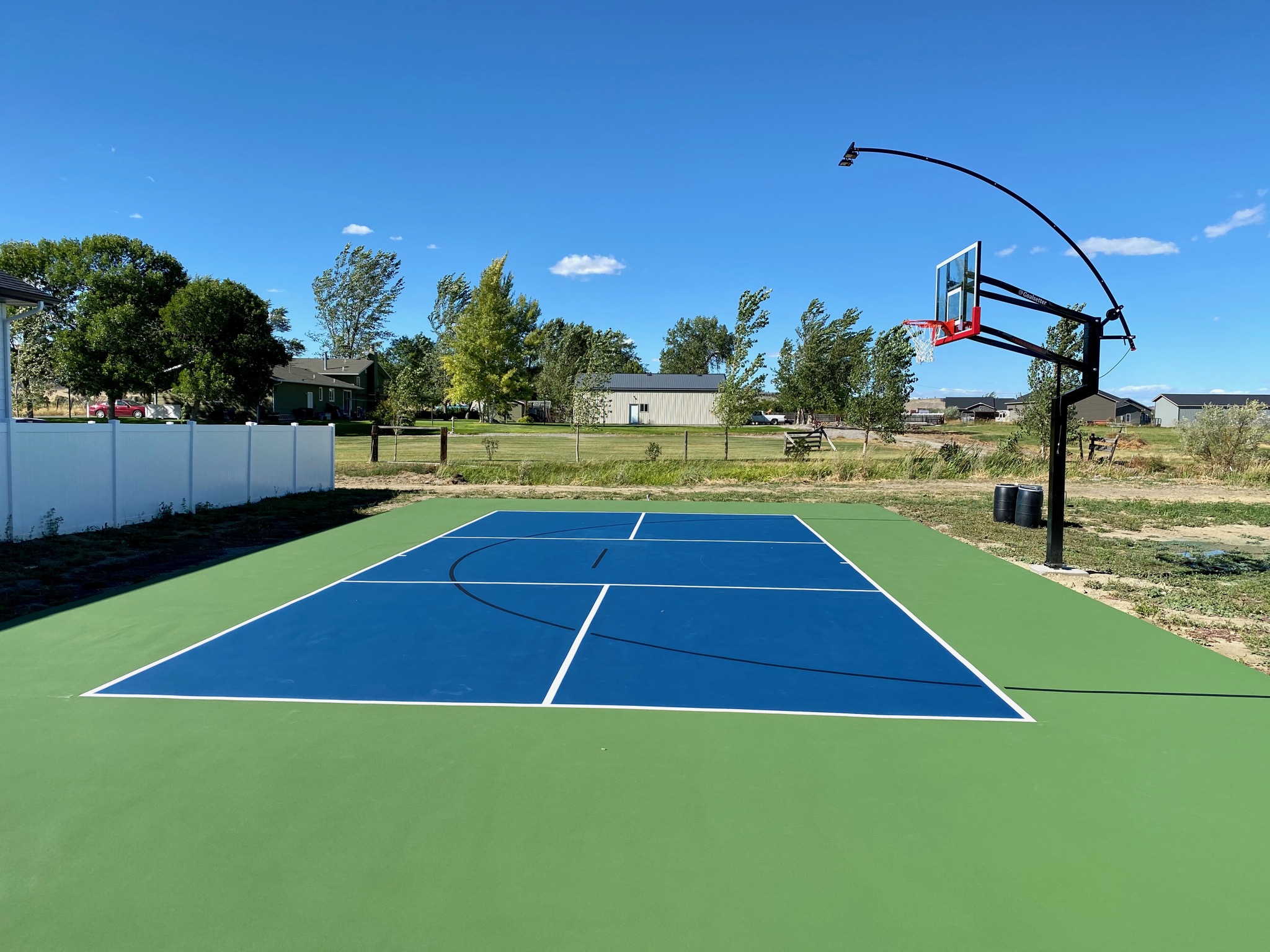 A new basketball and pickleball court withe a lighted hoop and green, white, and blue colors.