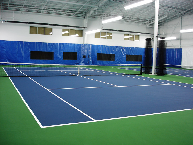 A newly surfaced indoor tennis court with green, blue, and white colors.